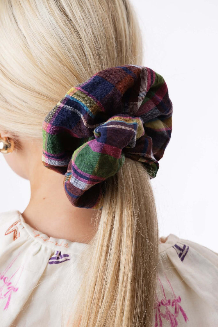 Checked fabric scrunchie tied around a ponytail, shown from behind to highlight colour, texture and scale.