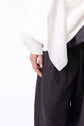 Close view of a white blouse and dark skirt, focusing on the drape of the sleeve and hand detail in the studio.