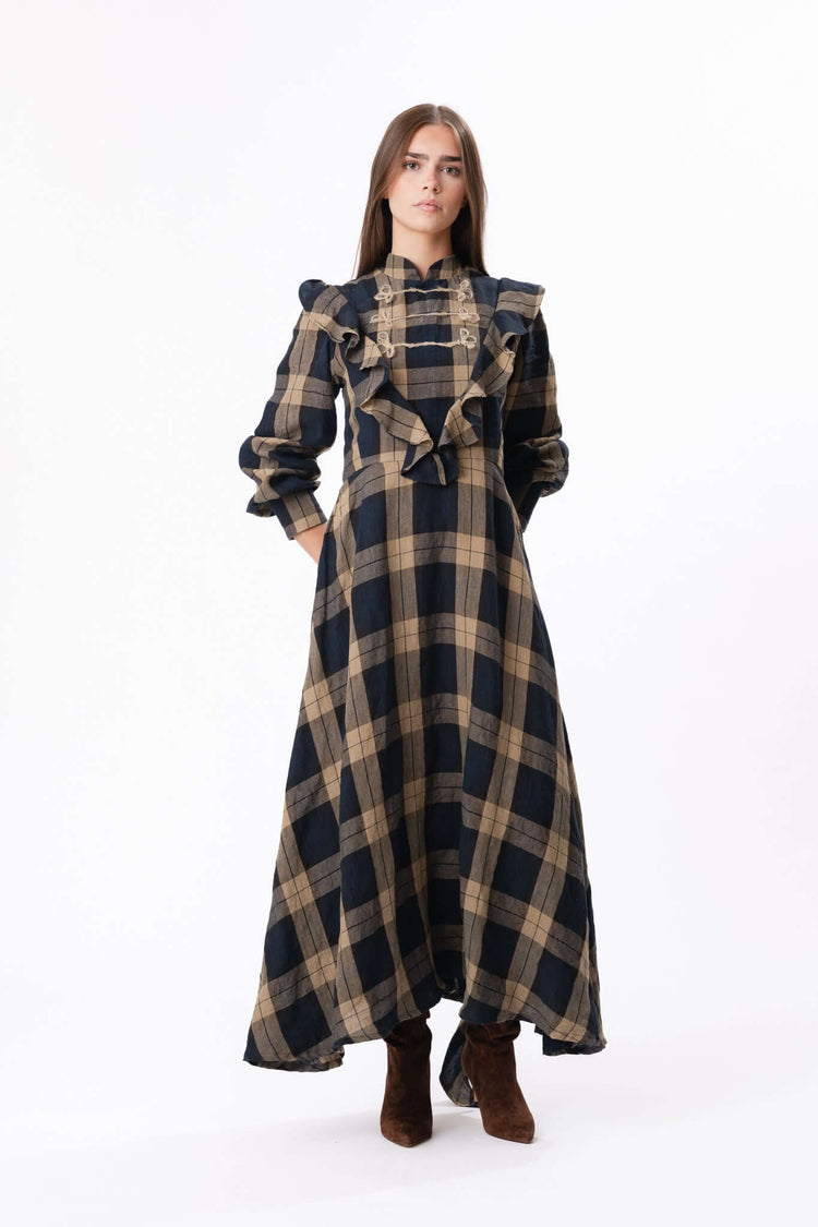Full-length checked dress with structured shoulders and long sleeves, shown against a plain studio backdrop.