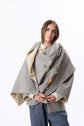 Model wearing a grey shawl layered over a shirt and trousers, shown front on in a clean studio setting.