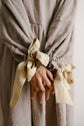 Close detail of gathered sleeve openings tied with bows, focusing on hand, fabric texture and movement.