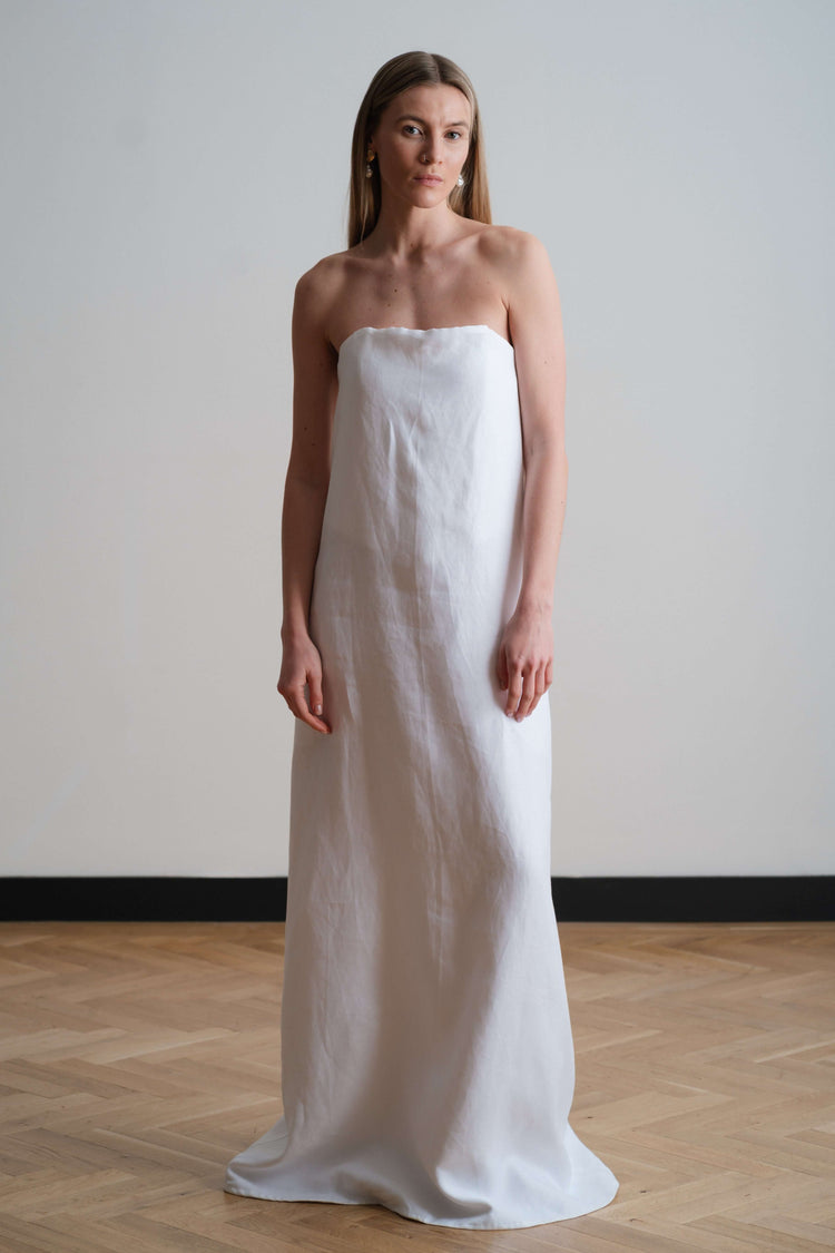 Full-length strapless white column dress, photographed front on to show clean lines and minimal silhouette.