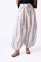 Close view of white striped balloon trousers tied at the waist, focusing on shape, folds and movement.