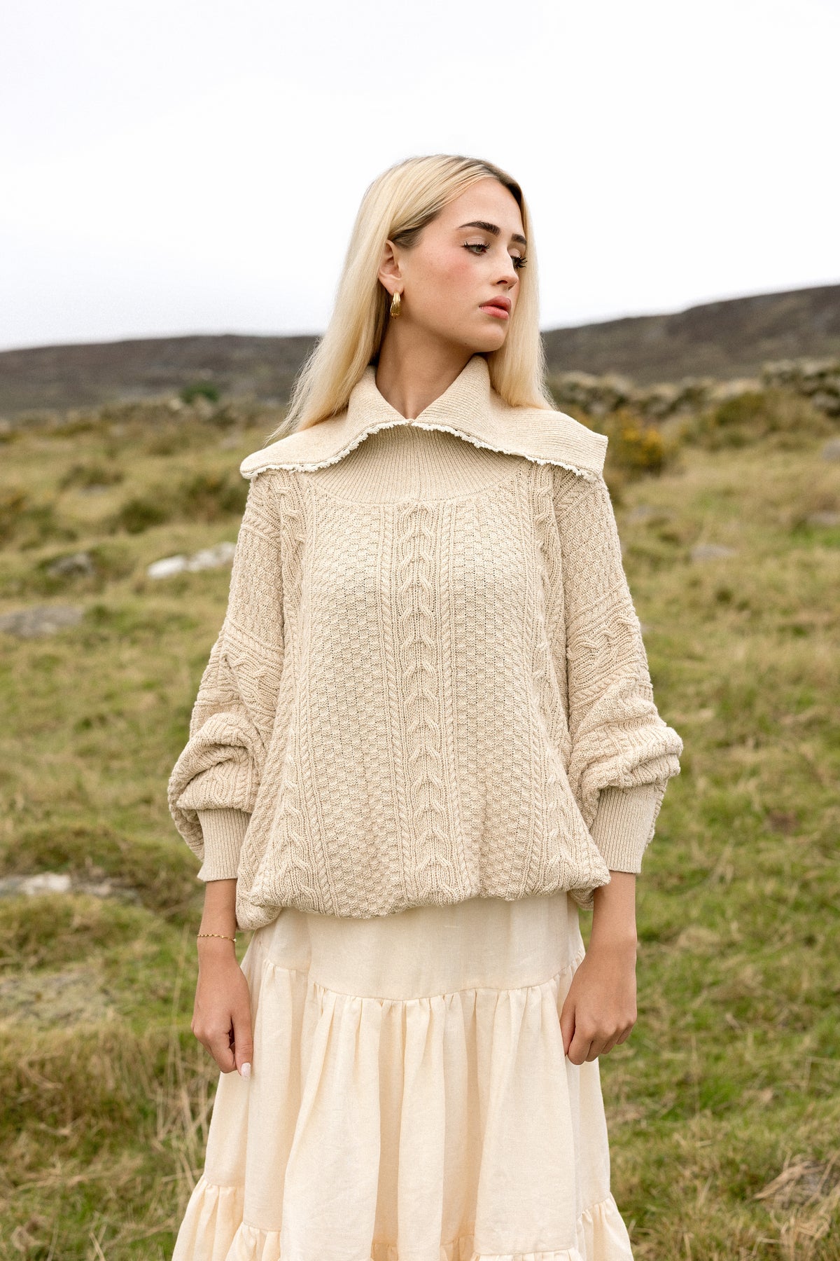 The Aran Jumper, a cream cable knit with a wide crochet-edged collar