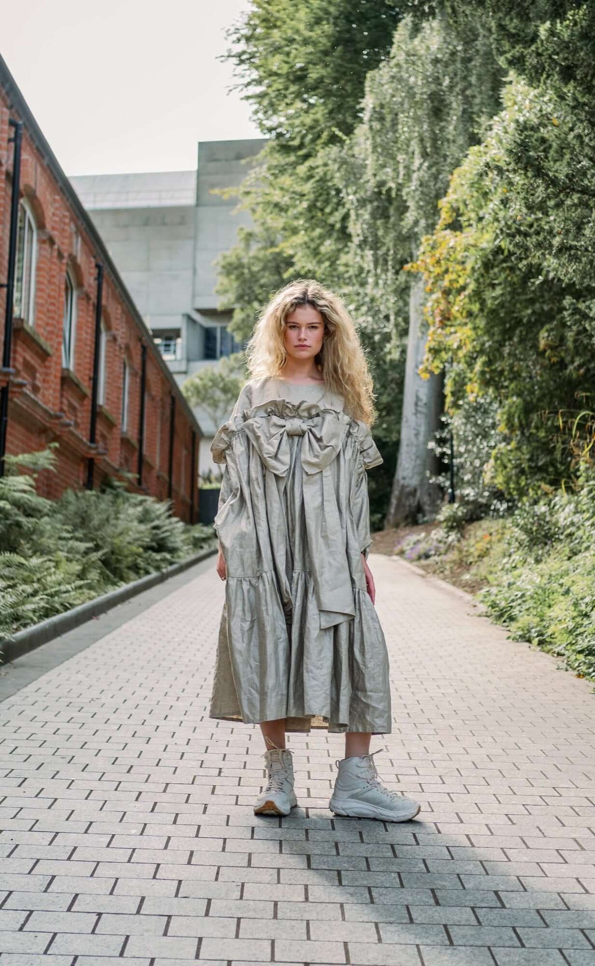 BOW DRESS | A new shape for AW23, The Bow Dress is one of our most playful. The dress is an oversized shape with gathered tiered details. The frill and bow detail at the front is the show-stopper. We have created this one in a beige/gold beetled linen whi